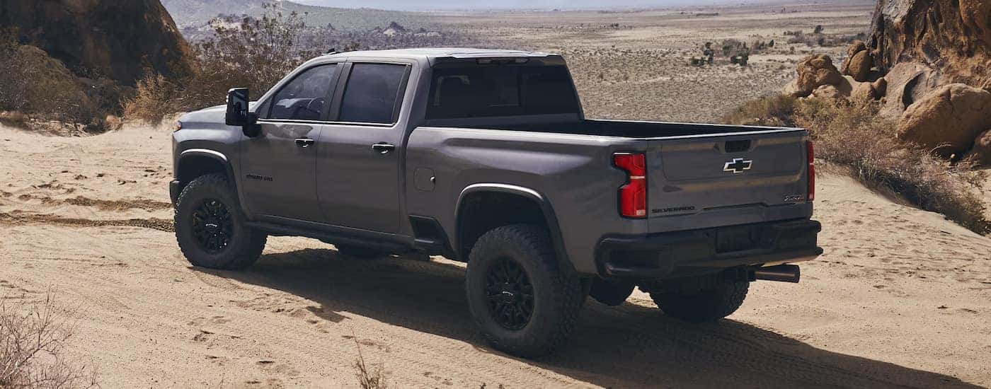 Rear view of a grey 2024 Chevy Silverado 2500 ZR2 parked in a sandy area.
