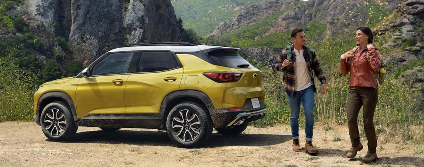 A yellow 2024 Chevy Trailblazer ACTIV is shown parked near two hikers.