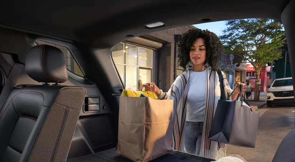 A woman loading groceries into the back of a 2024 Chevy Equinox RS for sale near Florence.