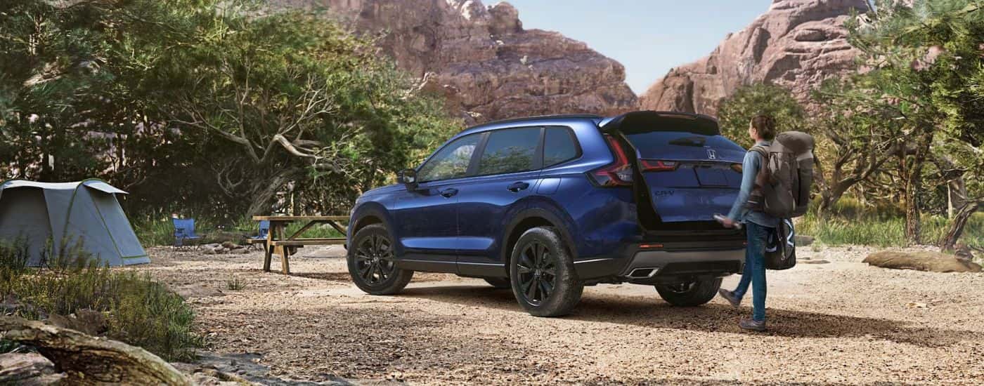 Blue 2026 Honda CR-V with a woman using the foot activated liftgate while parked at a capsite.
