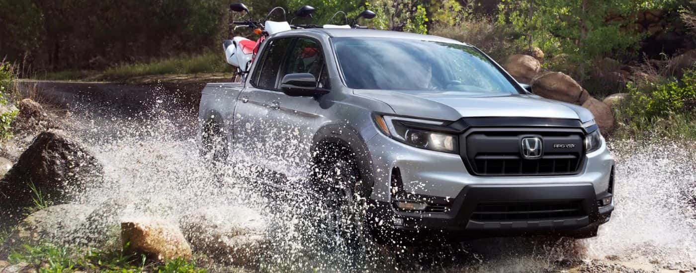 Silver 2026 Honda Ridgeline driving through a river.