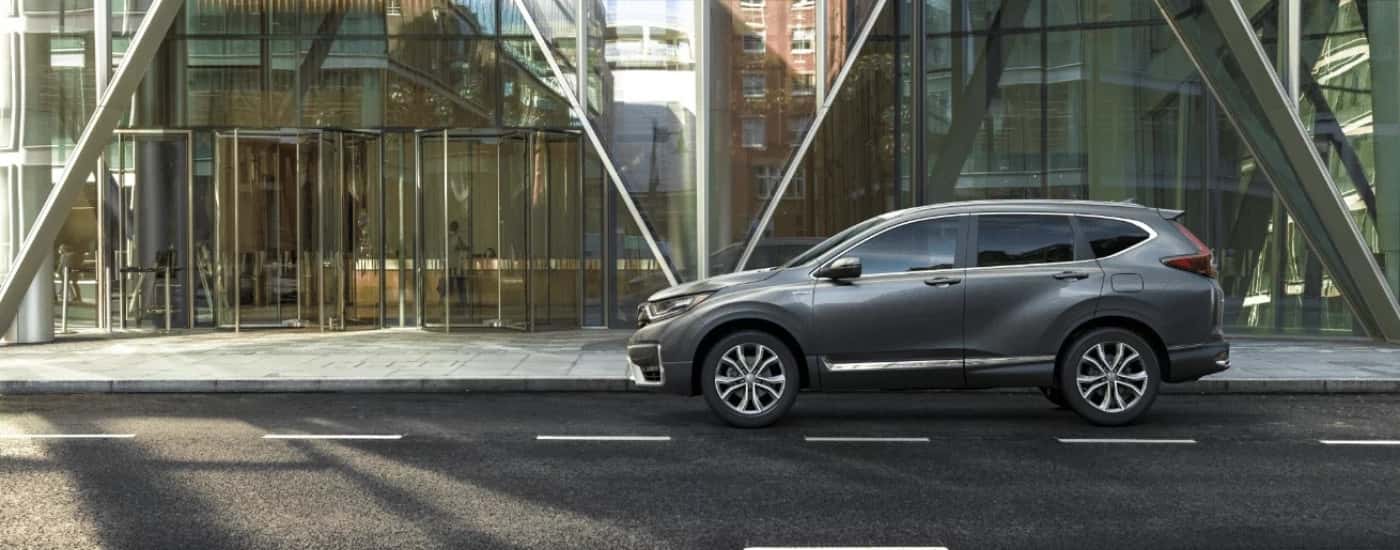 A gray 2022 Honda CR-V Hybrid Touring parked in front of a glass building.