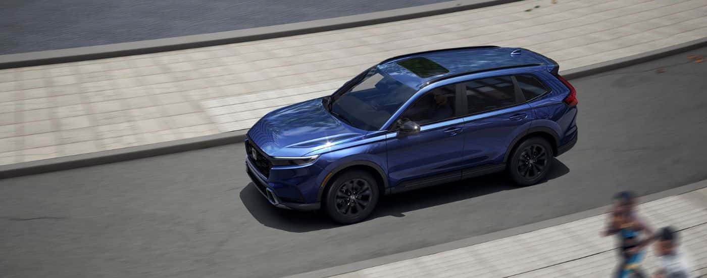 Aerial view of a blue 2026 Honda CR-V driving on a paved road.