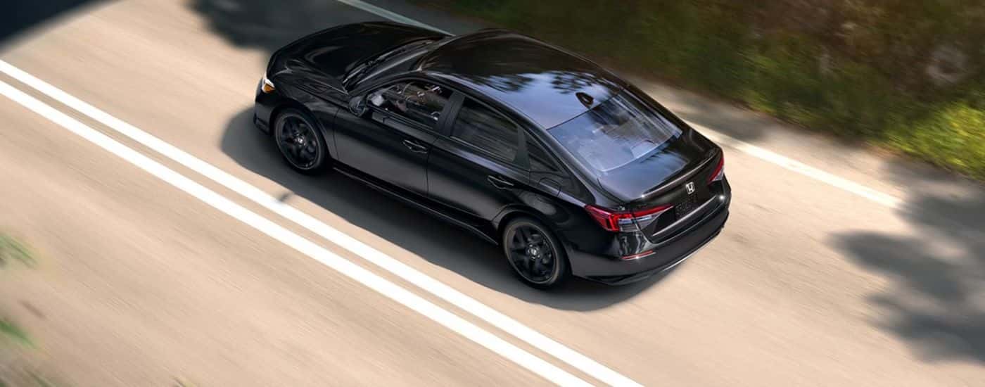 Aerial view of a black 2026 Honda Civic driving on a paved road.