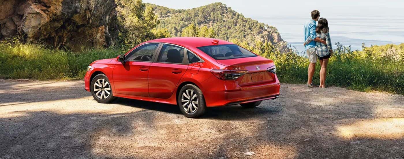 Red 2026 Honda Civic parked on a mountain with a couple overlooking the water.