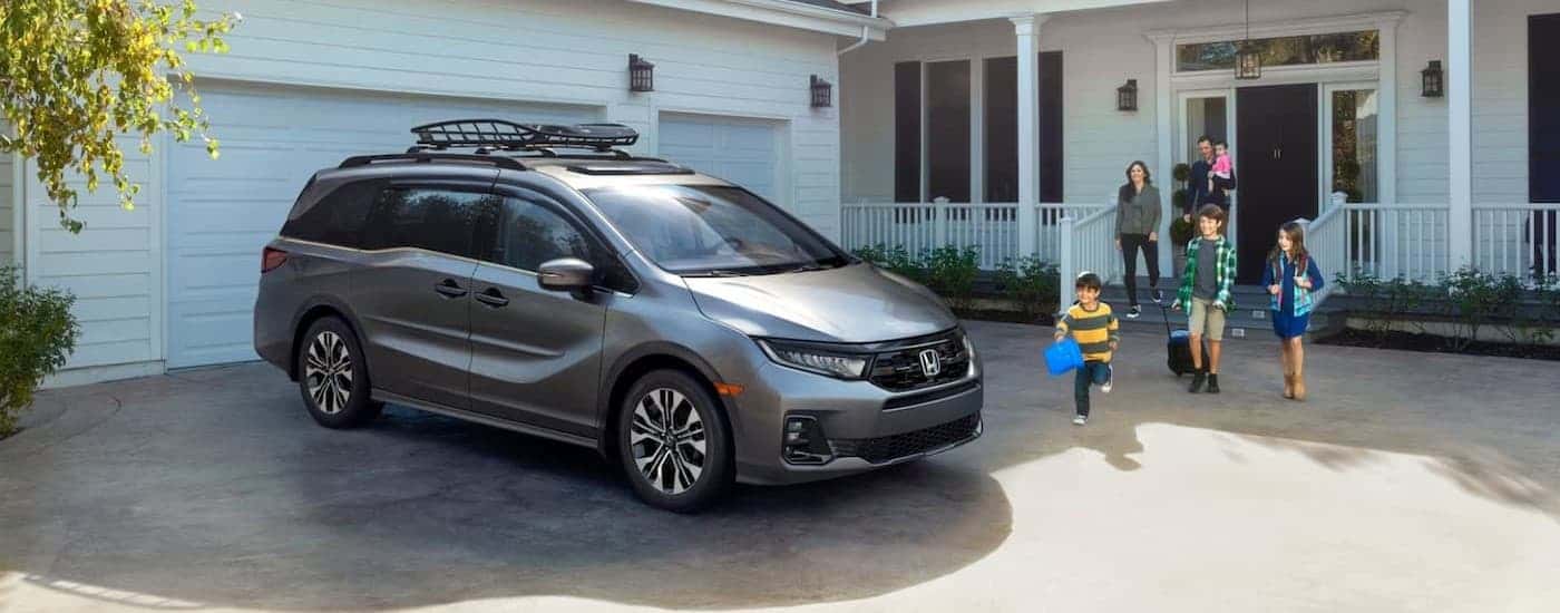 A silver 2025 Hond Odyssey parked near a family.