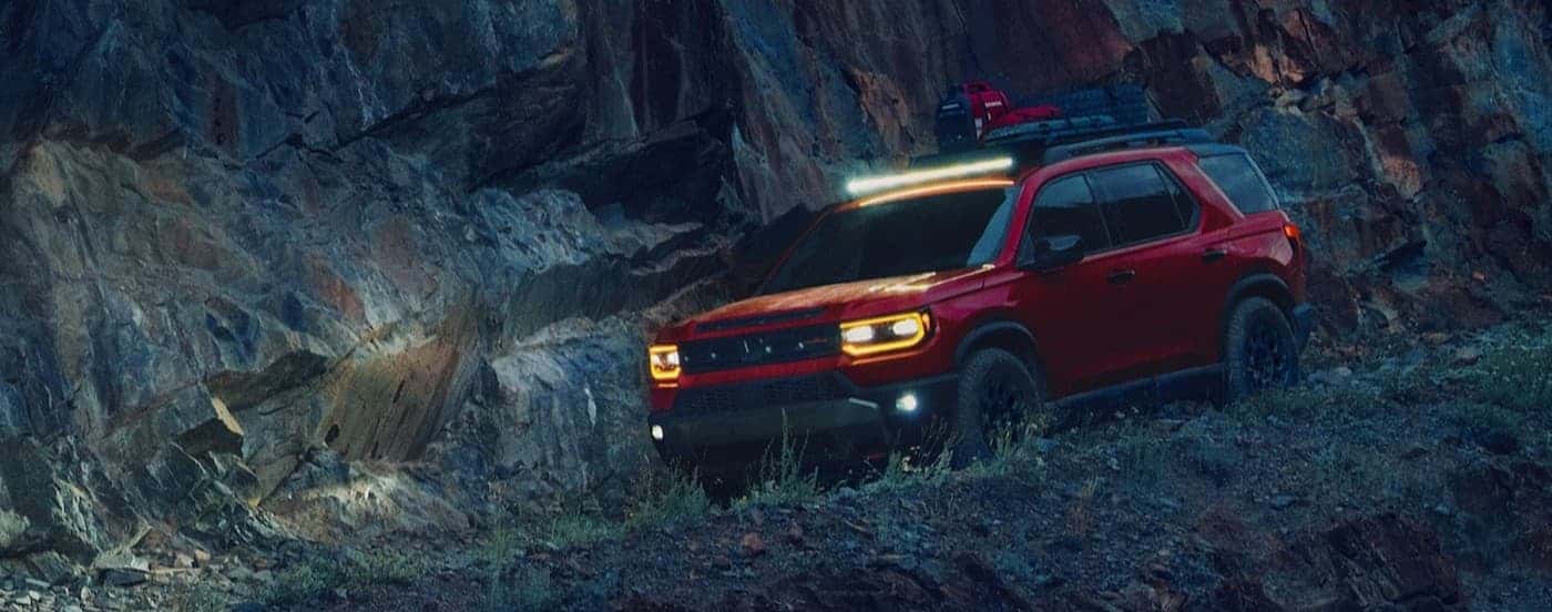 A red 2026 Honda Passport railSport Elite off-roading at night.