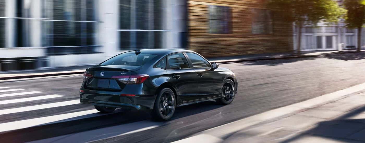 Black 2025 Honda Civic Hybrid Sport driving through a city