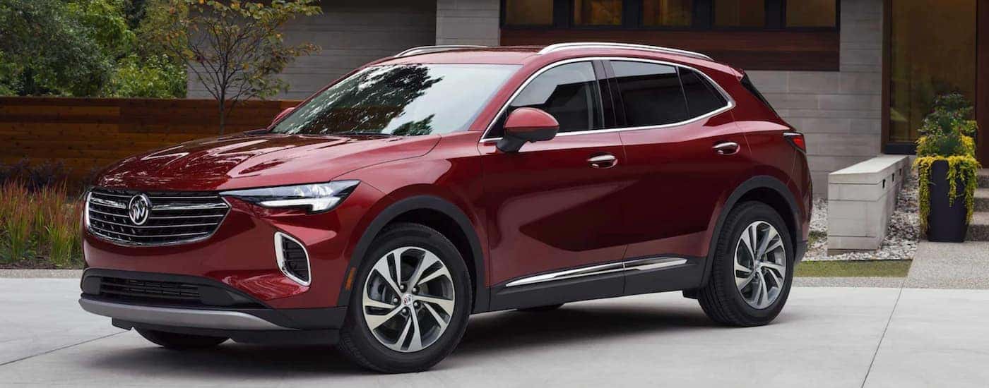 A maroon 2023 Buick Envision is shown from the side parked in front of a modern house.