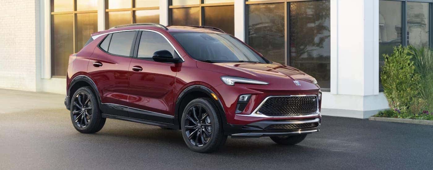 A red 2024 Buick Encore GX is shown from the side parked in front of a house.