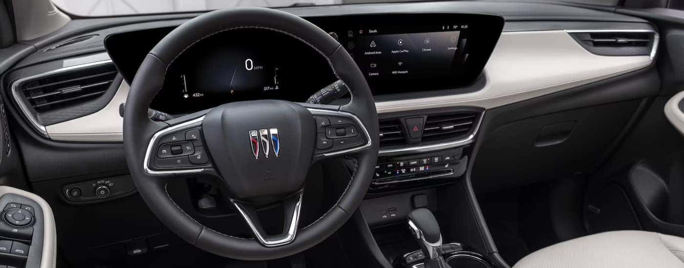 A black 2024 Buick Encore GX shows the steering wheel and infotainment screen.