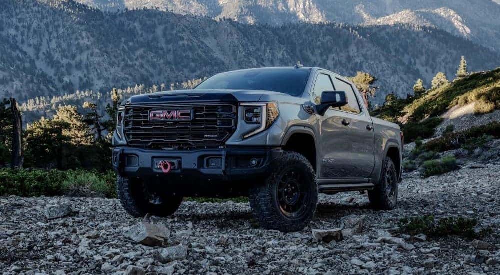 A grey 2024 GMC Sierra 1500 AT4X is shown parked near mountains.