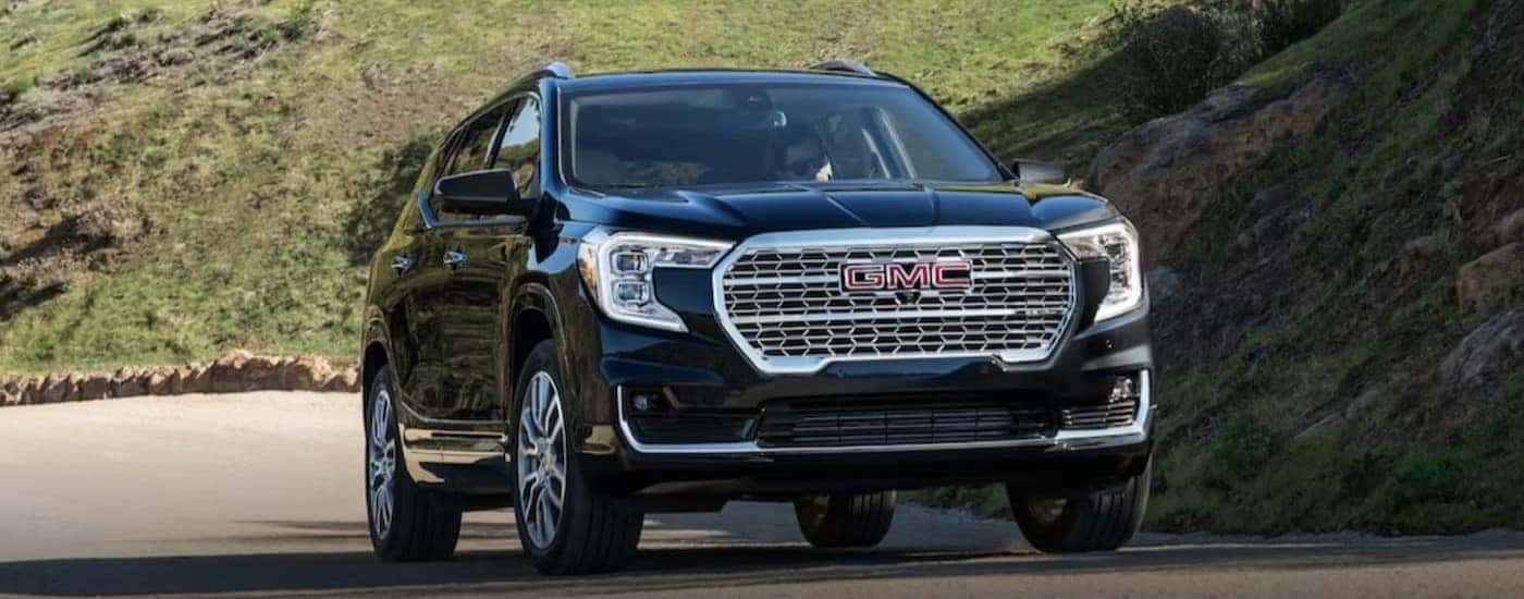A black 2024 GMC Terrain is shown driving on a road.