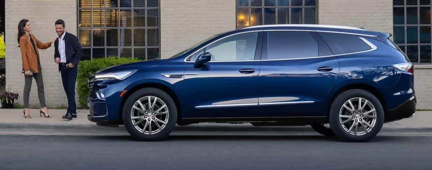 A blue 2024 Buick Enclave is shown parked near a curb.