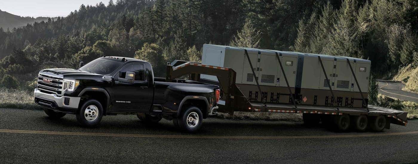 A black 2024 GMC Sierra 3500 HD is shown towing a trailer.