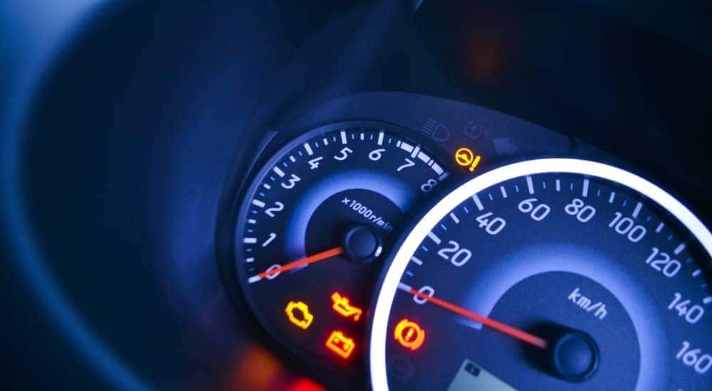 A set of warning lights are shown flashing on a speedometer.
