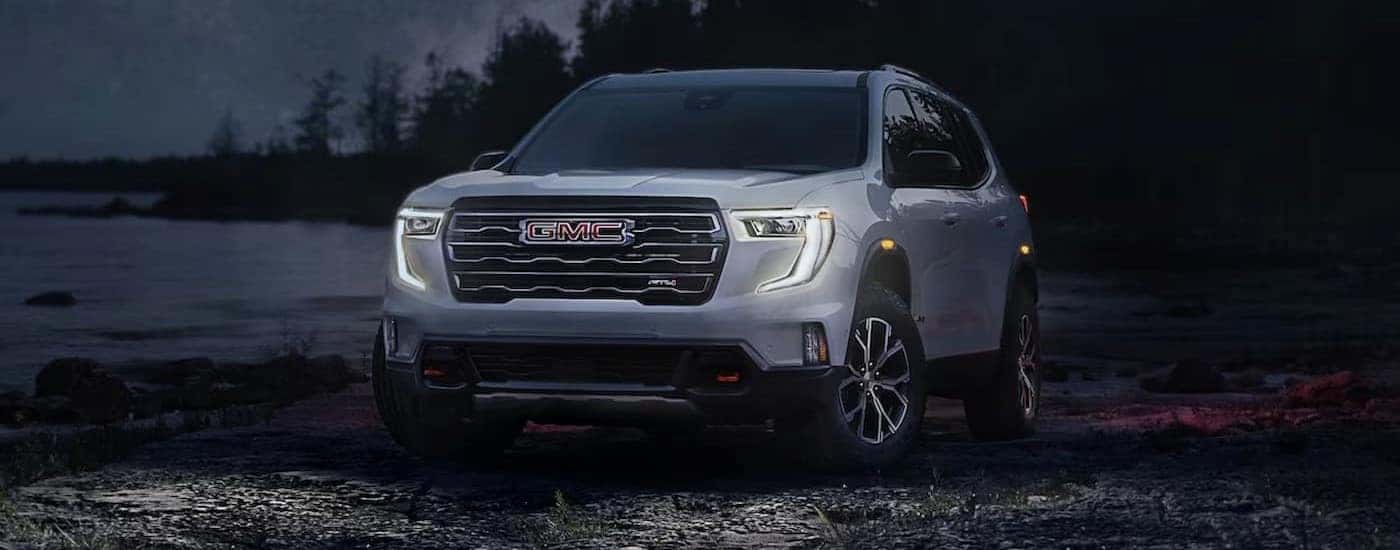 A silver 2024 GMC Acadia AT4 is shown parked at night.
