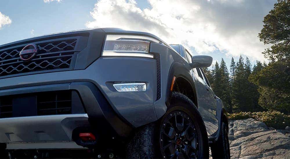 A close up of the headlight and front of a grey 2024 Nissan Frontier PRO-4X.