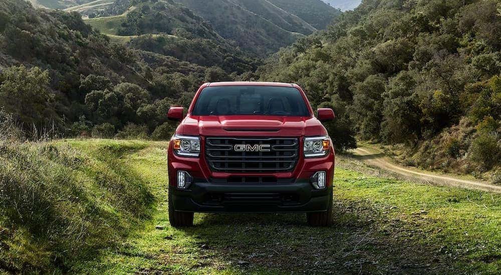 A red 2022 GMC Canyon Elevation parked on a grassy trail.