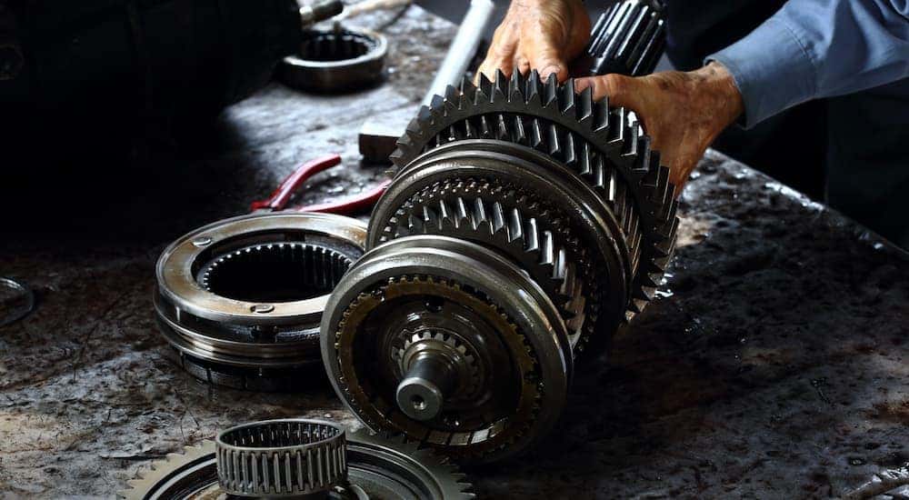 A mechanic is repairing a vehicle's transmission.