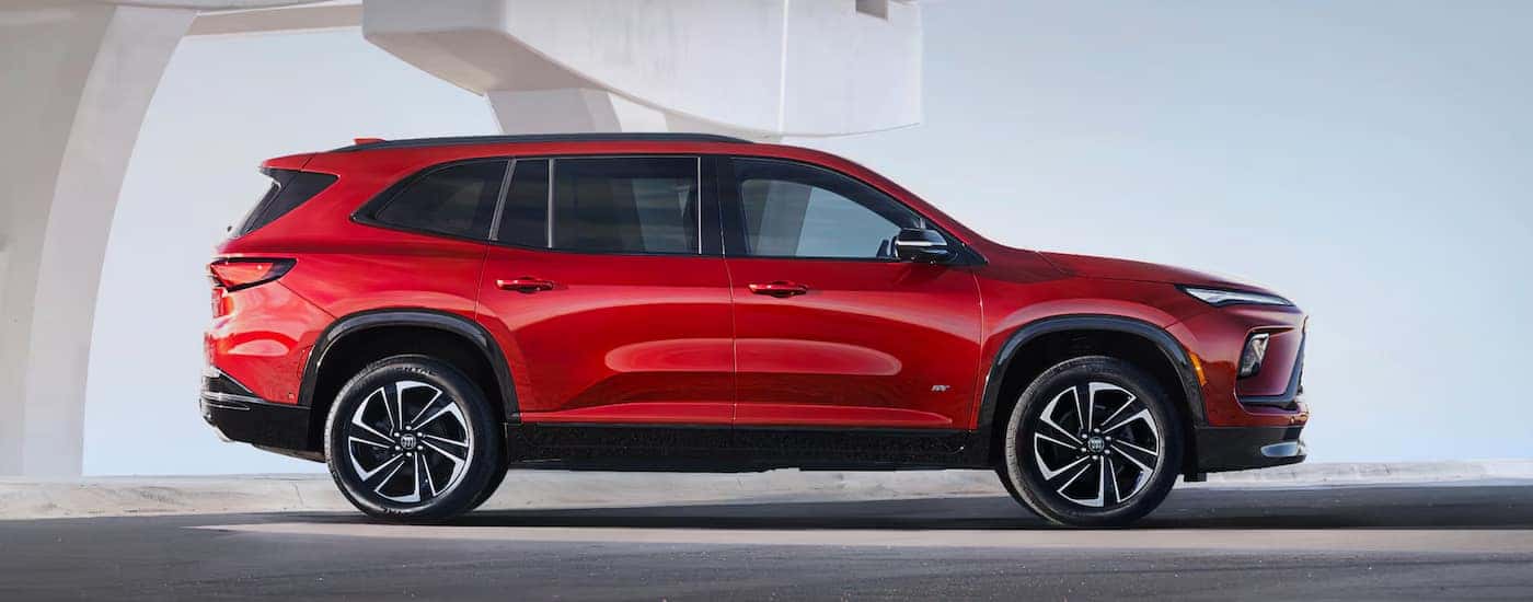 Side view of a red 2025 Buick Enclave ST parked under an overpass.