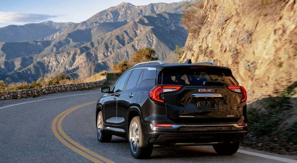 A black 2024 GMC Terrain Denali is shown from the rear at an angle.