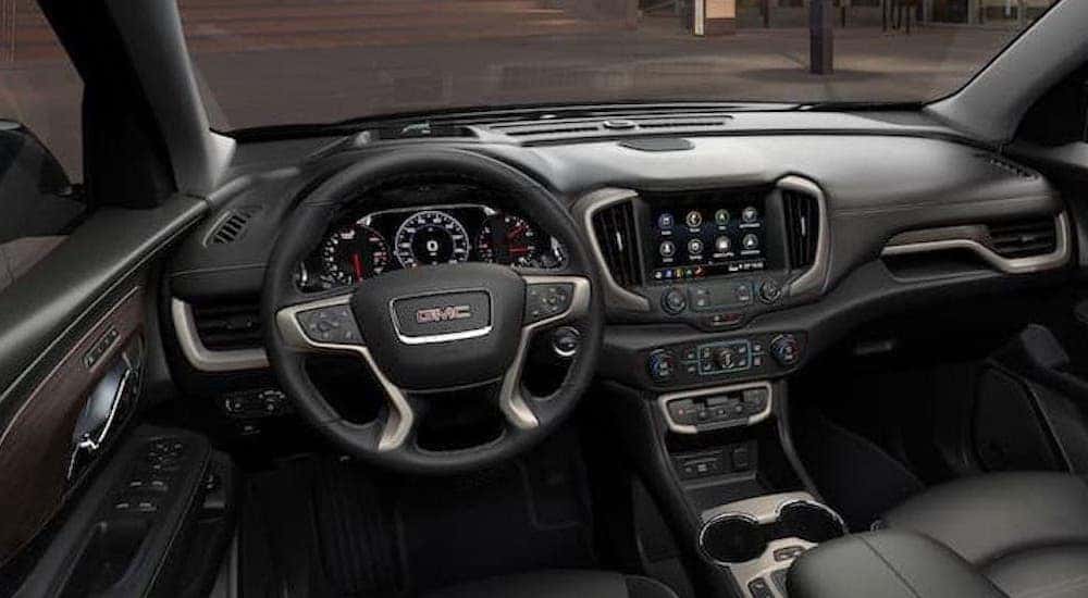 The black interior of a 2024 GMC Terrain for sale is shown from the driver's seat.