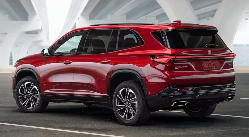A red 2025 Buick Enclave Sport Touring is shown parked under a bridge.