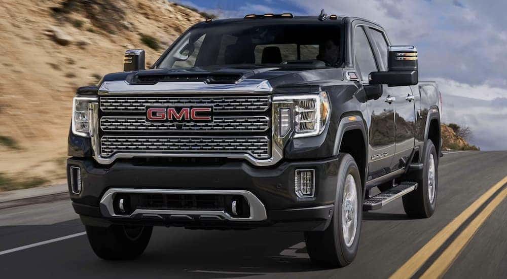 A black 2023 GMC Sierra 2500 HD Denali driving down a road.