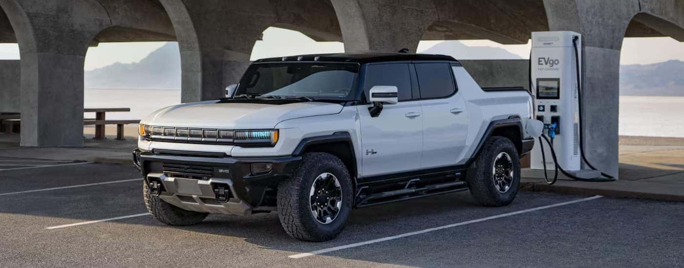 A white 2024 GMC Hummer EV Pickup plugged into an EVgo charging station.
