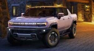 A white 2024 GMC Hummer EV Pickup parked in a courtyard at night.