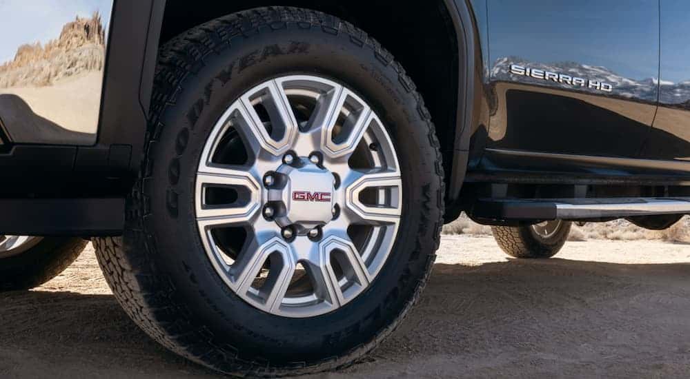 A close-up on the wheel of a black 2024 GMC Sierra 2500 HD for sale.