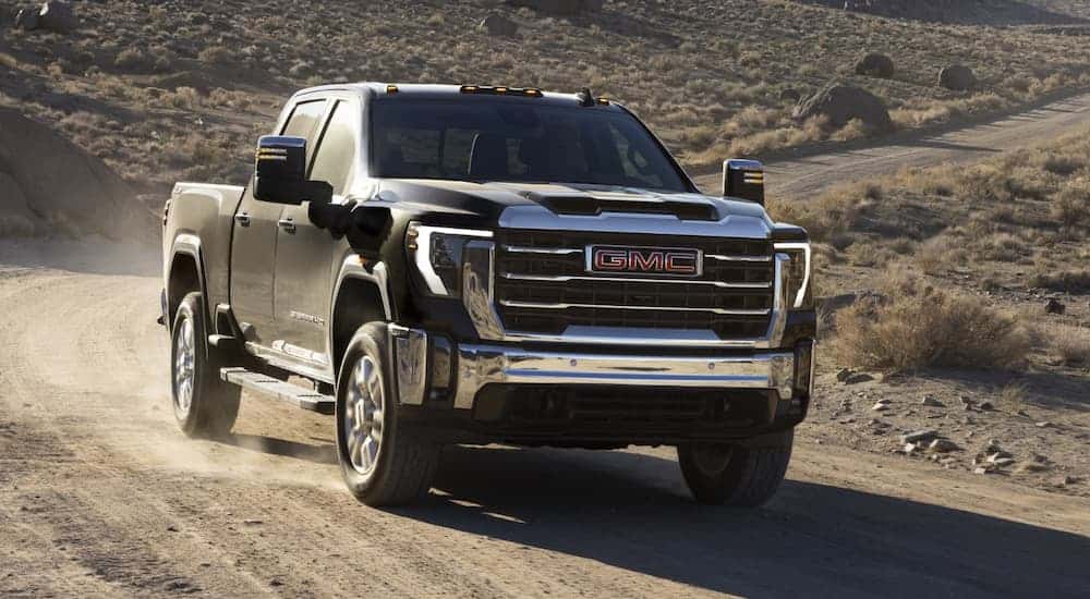 A black 2024 GMC Sierra 2500 HD Pro driving off-road on a trail.