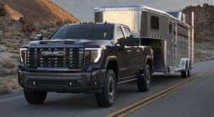 A black 2024 GMC Sierra 2500 Denali is shown towing a trailer to a GMC dealer near Johns Creek.