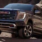 A grey 2025 GMC Yukon AT4 parked off-road and angled left.