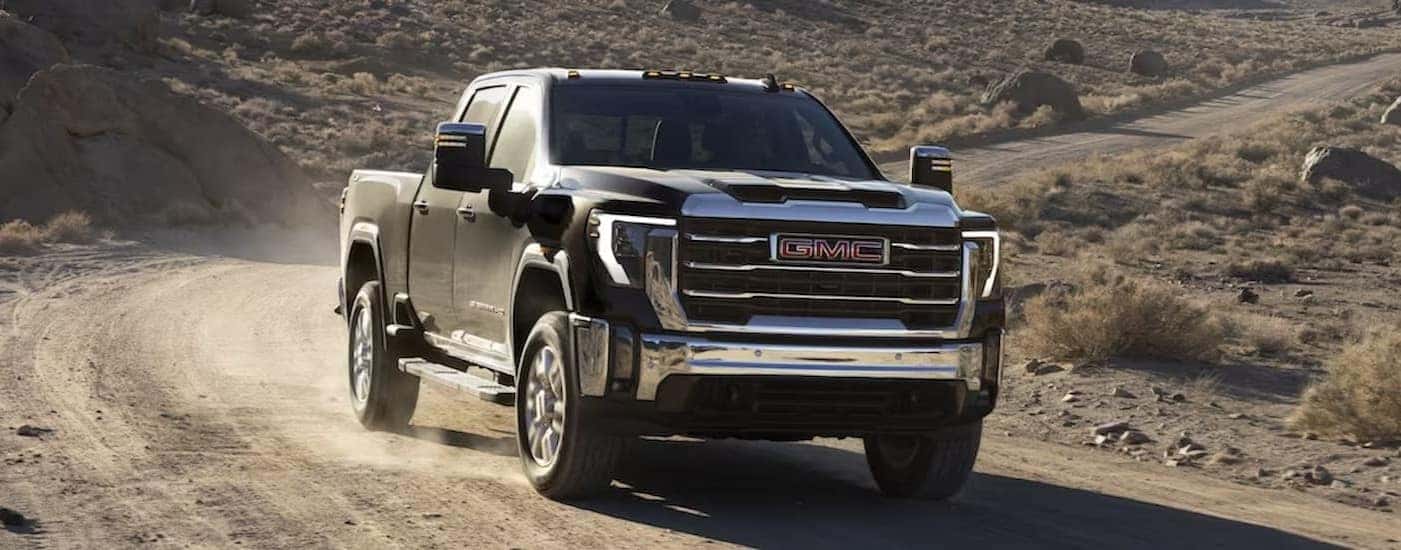 A black 2025 GMC Sierra 2500 HD is shown driving off-road.