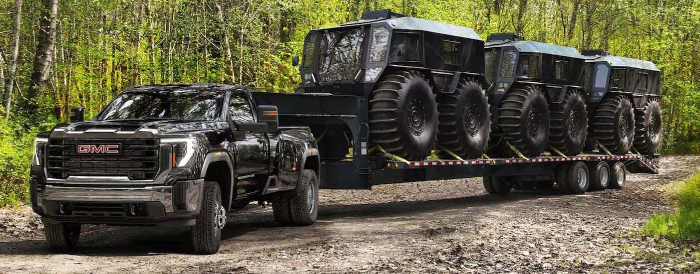 A black 2025 GMC Sierra 2500 HD is shown towing three SHERPS.