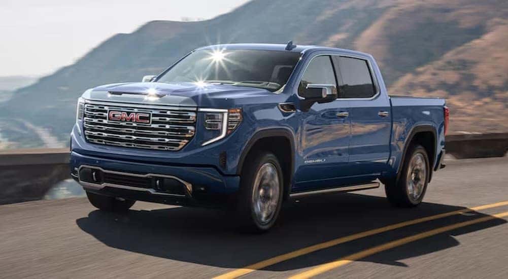 A blue 2025 GMC Sierra 1500 is shown driving on a highway.