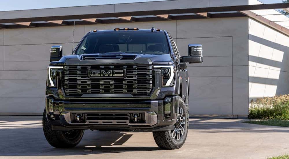 A black 2024 GMC Sierra 2500 HD Denali is shown from the front after leaving a dealer that has GMC Denali models.