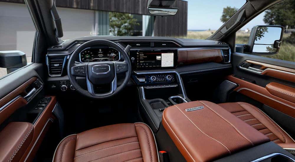 The brown interior of a 2024 GMC Sierra 2500 HD Denali Ultimate is shown from the driver's seat.