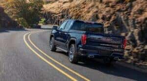 A blue 2024 GMC Sierra 1500 is shown from the rear at an angle after leaving a dealer that has a GMC Sierra for sale.