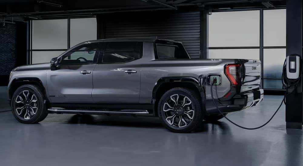 Side view of a silver 2025 GMC Sierra EV Denali charging inside.