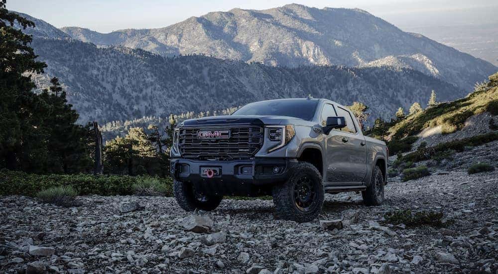 A grey 2024 GMC Sierra AT4x AEV is shown from the front at an angle after leaving a dealer that has a GMC Sierra for sale.
