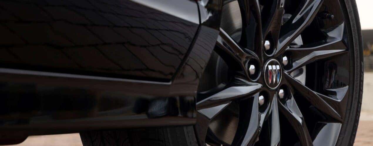 A close-up shows a black wheel on a black 2025 Buick Encore GX ST.