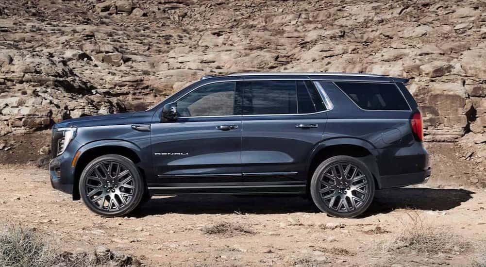A blue 2025 GMC Yukon XL Denali is shown parked off-road.
