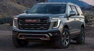 A grey 2025 GMC Yukon XL AT4 parked in front of mountains.