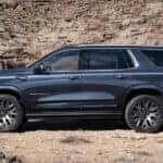 Side angle view of a blue 2025 GMC Yukon XL Denali parked off-road.