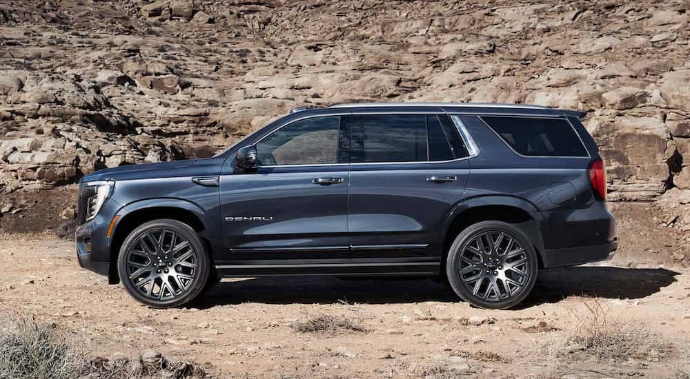 Side angle view of a blue 2025 GMC Yukon XL Denali parked off-road.