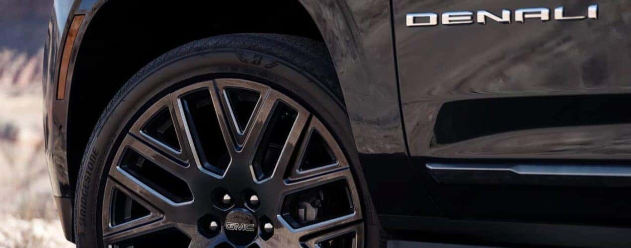 A close-up of the wheel is shown on a black 2025 GMC Yukon Denali.