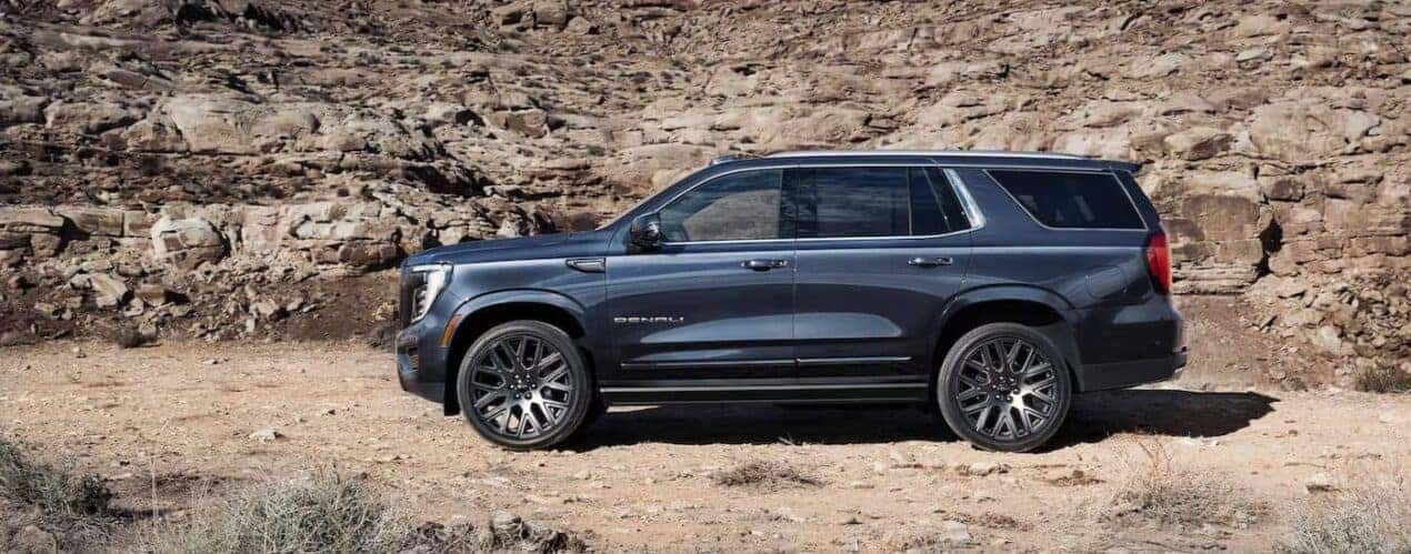 A blue 2025 GMC Yukon Denali is shown parked off-road.